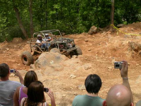 1990 Ford Bronco - Spectators watch an off-road buggy navigate a rocky terrain during an event.