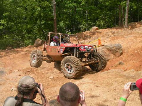 1990 Ford Bronco - A custom-built off-road buggy navigates a challenging rocky incline during an event.