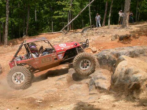 1990 Ford Bronco - A custom-built off-road buggy navigates a rocky terrain during an event.