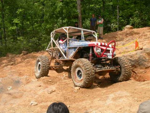 1990 Ford Bronco - A custom-built buggy navigates a steep, rocky incline during an off-road event.