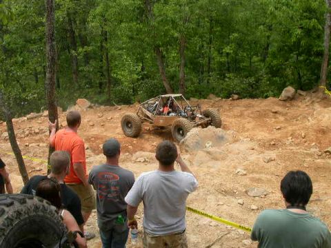 1990 Ford Bronco - Spectators observe an off-road buggy traversing a challenging rocky terrain during an event.