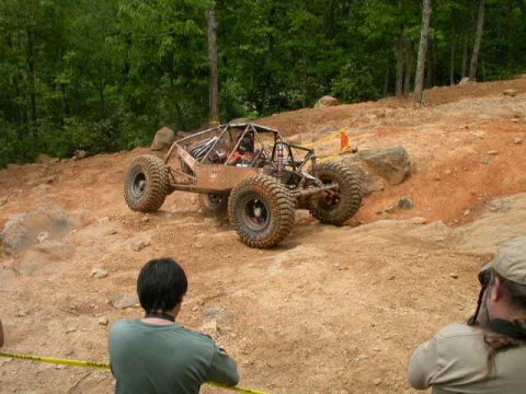 1990 Ford Bronco - A custom buggy navigates a challenging off-road course with spectators watching.
