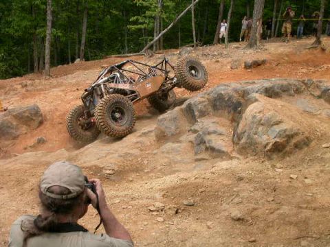 1990 Ford Bronco - A custom off-road buggy navigates a challenging rocky incline during an event.