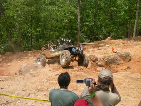 1990 Ford Bronco - A custom off-road buggy navigates a challenging rocky incline during a race event, while onlookers capture the action.