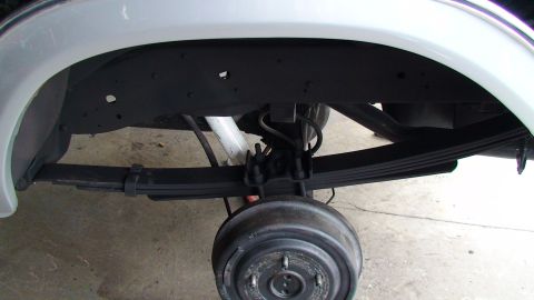 1979 Ford Bronco - Close-up view of the rear axle, leaf springs, and drum brake components.