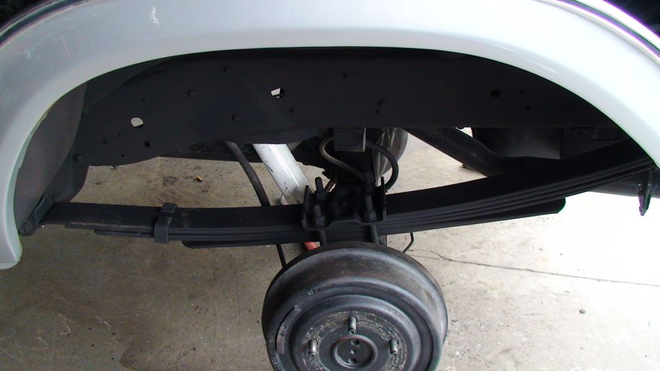 Rear axle assembly with leaf springs and drum brake visible