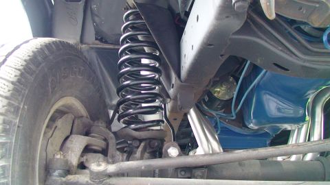 1979 Ford Bronco - Close-up of the front suspension and exhaust components of a vehicle.