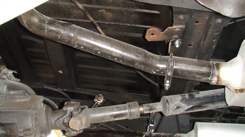 1979 Ford Bronco - A close-up view of the undercarriage reveals the exhaust system and drivetrain components of a vehicle.