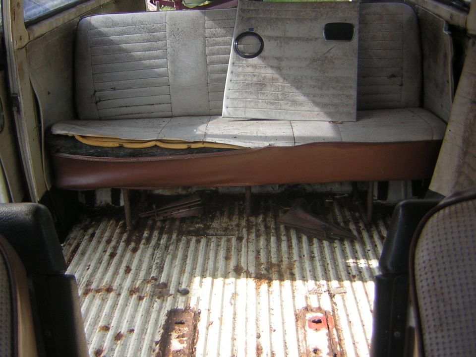 Interior of a van with worn seats and a ribbed metal floor