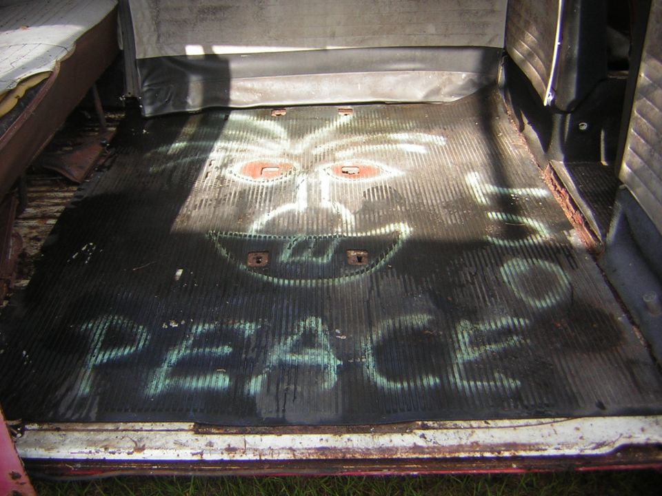 Van floor with spray-painted smiley face and 'PEACE' text