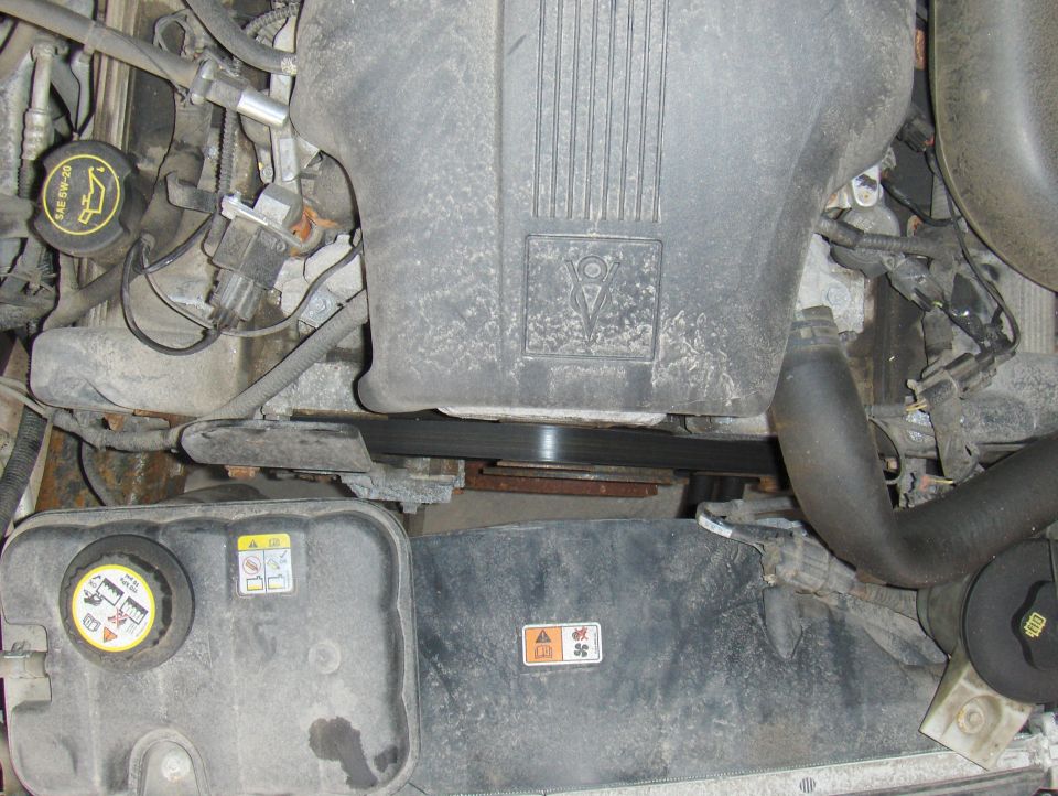 Engine bay with coolant reservoir and belt