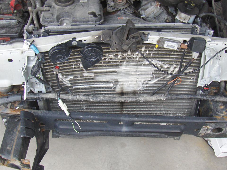 Damaged radiator and engine components in a white vehicle's engine bay