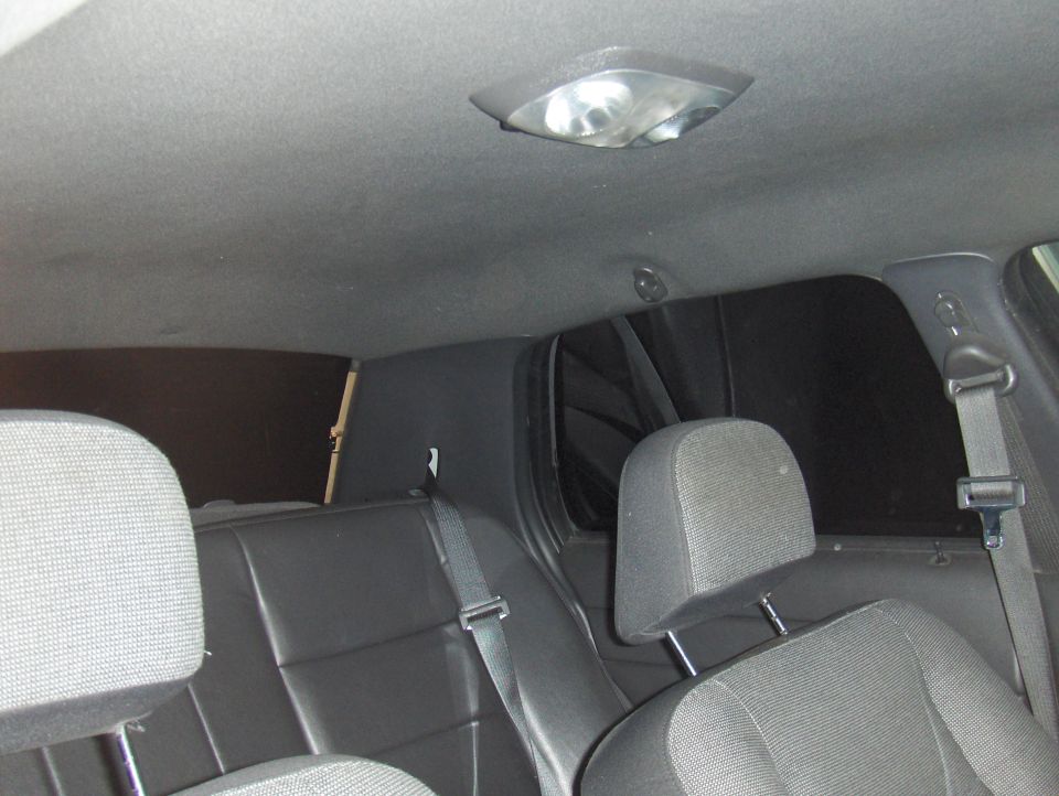 Rear seats and headrests visible inside a car, with tinted windows and a dome light on the ceiling