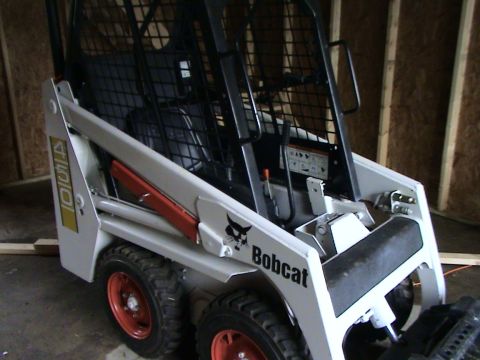 1946 Ford F1 - A white Bobcat skid steer loader is parked indoors with wooden walls in the background.