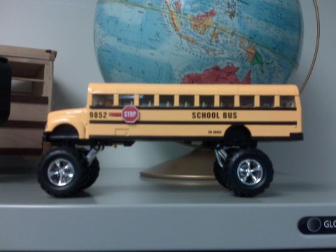 1996 Ford Bronco - Toy school bus modified with large monster truck wheels sits on a shelf.
