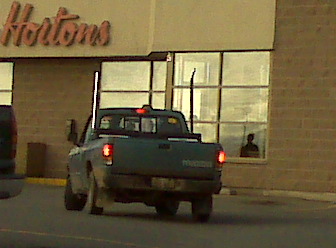 1996 Ford Bronco - A pickup truck with dual exhaust stacks drives past a Tim Hortons.