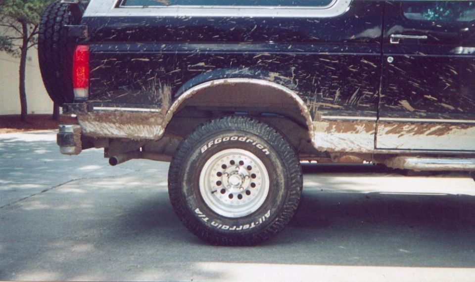 Side view of a dirty black SUV with a spare tire on the back and BFGoodrich All-Terrain tires