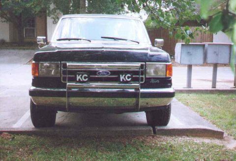 1990 Ford Bronco - This Ford F-Series truck features a prominent chrome grille with custom plates and the Ford emblem, indicating a model year from the late 1…