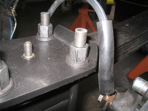 1979 Ford Bronco - Detail of a vehicle's suspension system, focusing on the leaf spring and brake line connection.