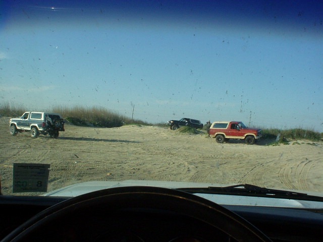 1990 Ford Bronco and two other SUVs parked on sand dunes under a clear blue sky