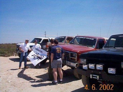 1990 Ford Bronco - Ford Bronco club members gather with their vehicles and a club banner.