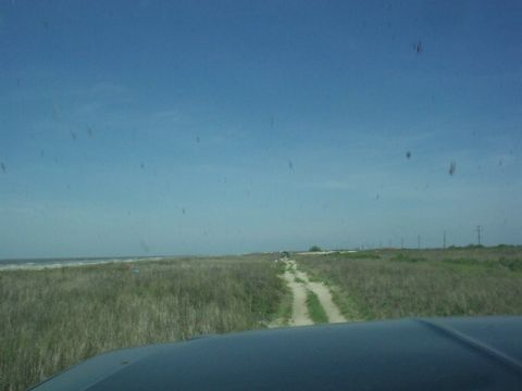 1990 Ford Bronco - Driving down a sandy path towards the ocean on a clear day.
