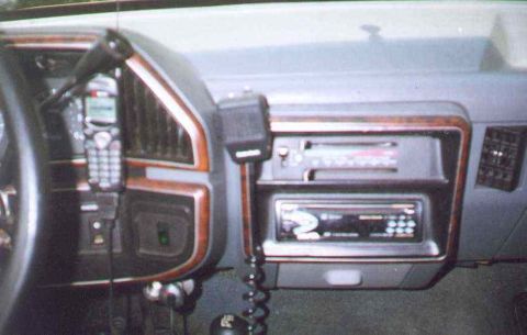 1990 Ford Bronco - The interior of a vehicle shows an aftermarket radio and a mounted mobile phone.