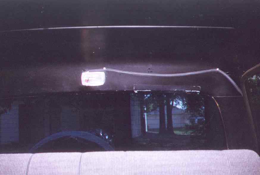 Interior overhead light fixture and rear window view of trees and houses