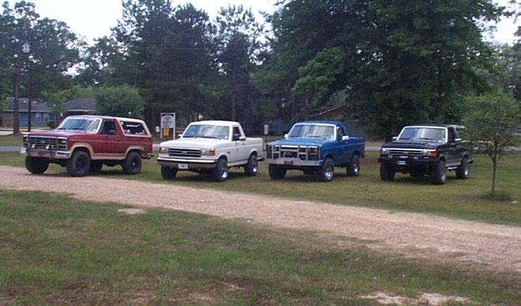 Four Ford trucks and SUVs parked in a line.