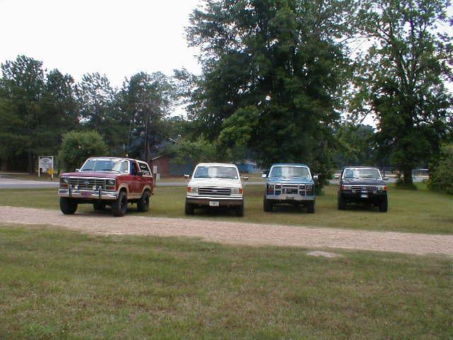Four SUVs parked in a line on a gravel driveway.