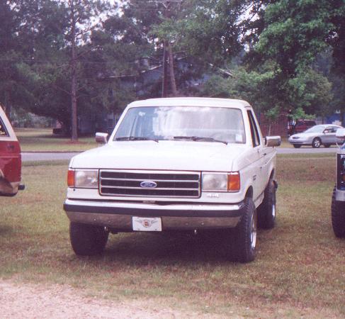 White 1990 Ford Bronco parked on grass, front view.