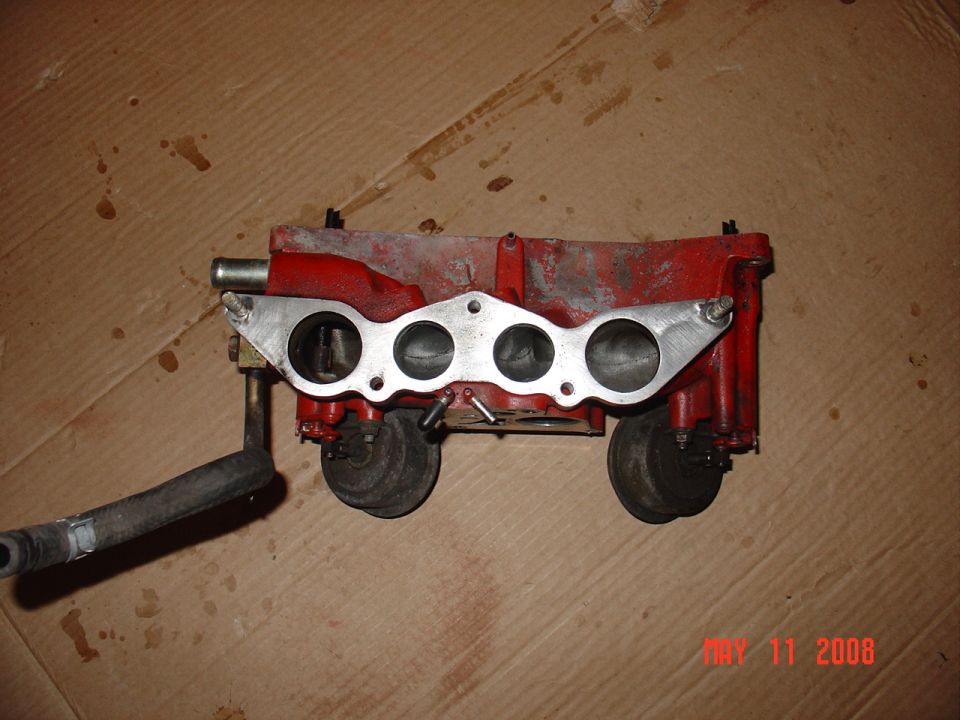 Red intake manifold with black hose attached.