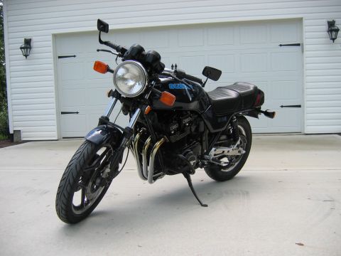 1985 Ford LTD Crown Victoria - Photograph of a black Suzuki motorcycle in front of a garage, not a technical document.