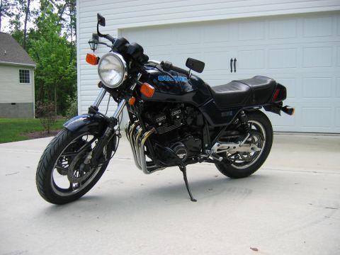 1985 Ford LTD Crown Victoria - Photograph of a black Suzuki motorcycle on a driveway, not a technical document.