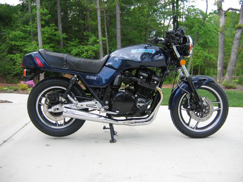 Blue Suzuki motorcycle parked on a driveway with trees behind