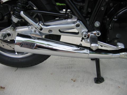 1985 Ford LTD Crown Victoria - Photograph of a motorcycle exhaust muffler and footpeg, not a technical document.