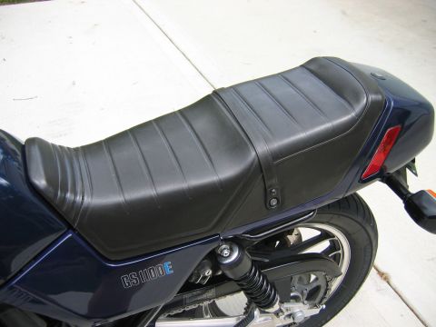 1985 Ford LTD Crown Victoria - Close-up view of the seat and side panel of a Suzuki GS1100E motorcycle.