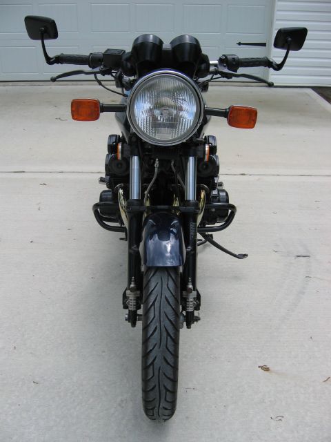 1985 Ford LTD Crown Victoria - A dark motorcycle is shown from the front, dual headlights and prominent orange turn signals.