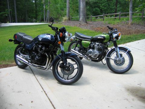 1985 Ford LTD Crown Victoria - Two motorcycles are parked side-by-side on a concrete surface with a grassy area and trees in the background.