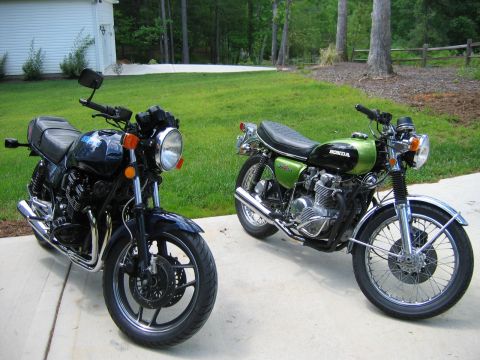 1985 Ford LTD Crown Victoria - Two motorcycles are parked on a concrete driveway in front of a house and grassy yard.