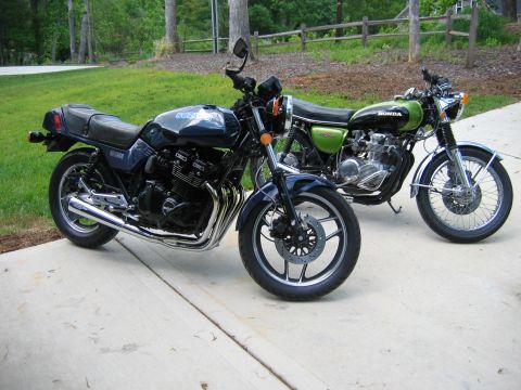 1985 Ford LTD Crown Victoria - Two motorcycles parked on a concrete driveway with a grassy area and fence in the background.