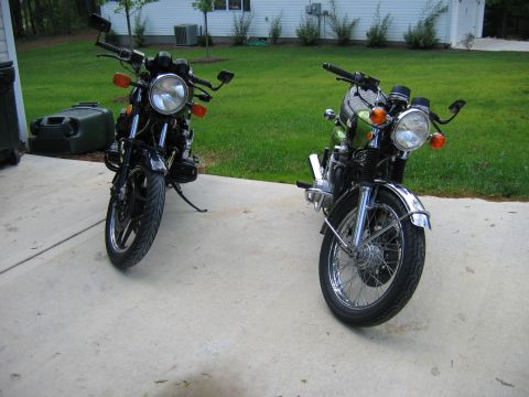 1985 Ford LTD Crown Victoria - Two motorcycles are parked outside a house on a sunny day.