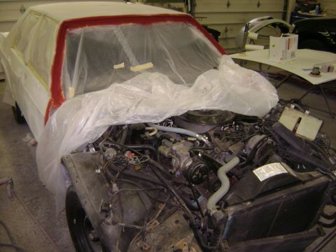 2001 Ford Crown Victoria - A car is undergoing repairs in a garage, with its engine compartment open and parts covered.