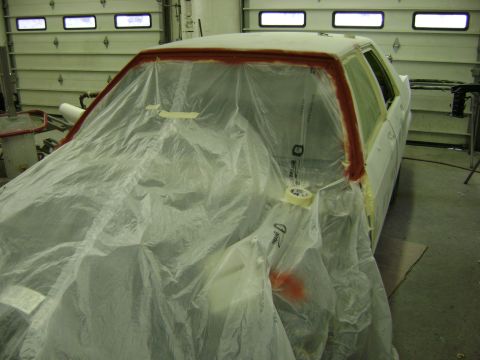 2001 Ford Crown Victoria - A car is covered in plastic sheeting and tape in a garage, likely undergoing repairs or painting.