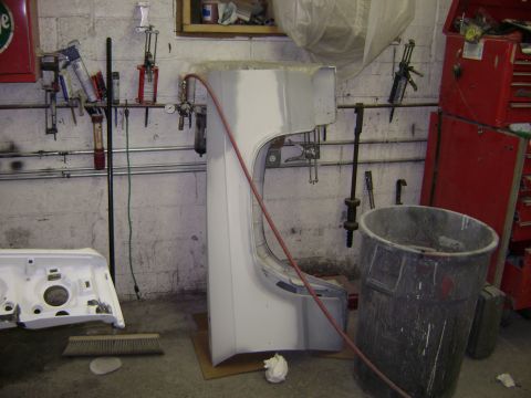 2001 Ford Crown Victoria - Car body parts, including a fender and front end assembly, are laid out in a garage workshop.
