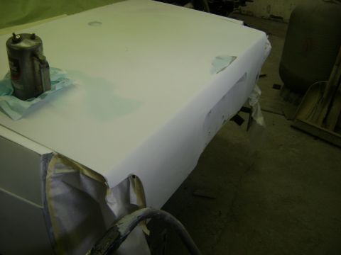 2001 Ford Crown Victoria - A car body is being prepped for paint, with a primer coat applied and some masking tape visible.