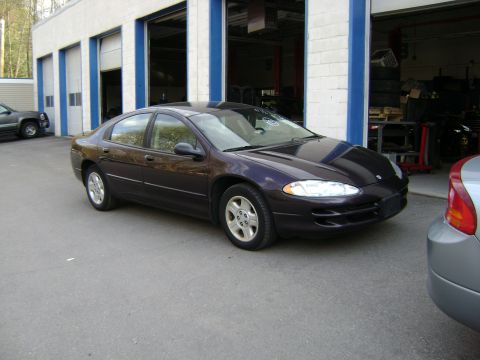 2001 Ford Crown Victoria - A dark purple Dodge Intrepid is parked outside a garage, with a silver car partially visible on the right.