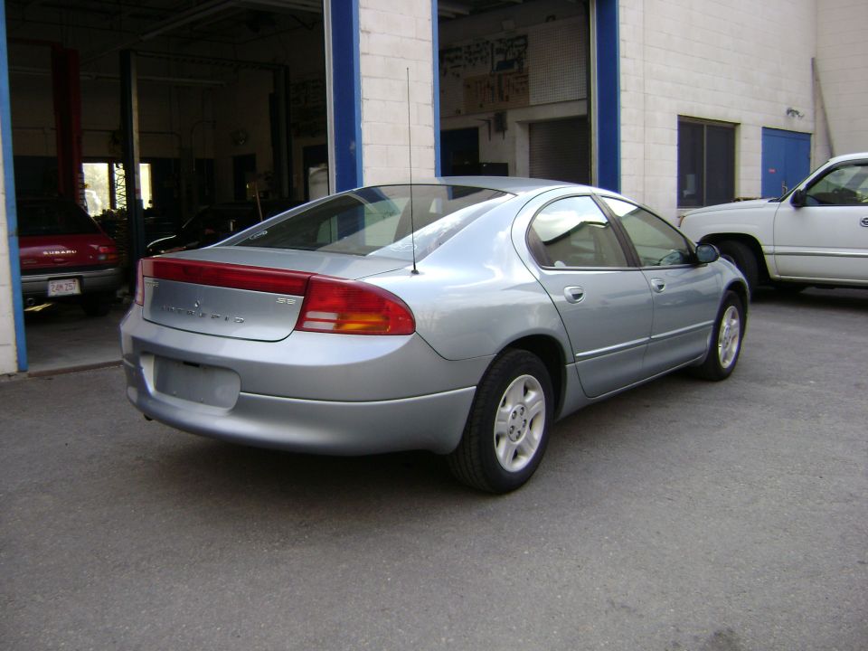 Silver Dodge Intrepid parked outside a garage, with a white pickup truck to its right and a red car inside the garage