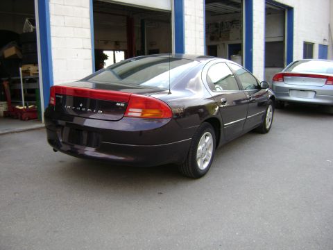 2001 Ford Crown Victoria - A dark purple Dodge Intrepid is parked in front of garage bays, with another silver sedan behind it.