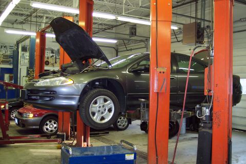 2001 Ford Crown Victoria - A dark gray Dodge Intrepid is raised on a lift in a garage, with its hood open.